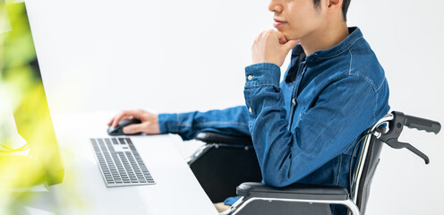 パソコンを使う男性身体障害者・車椅子