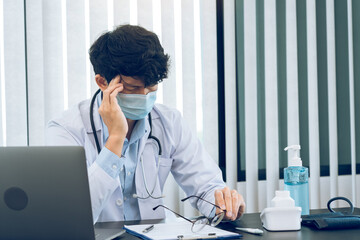 Asian young man doctor being exhausted and burnout in the office room.