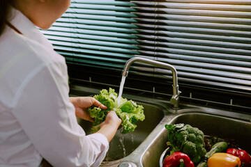 Asian hands woman washing vegetables salad and preparation healthy food in kitchen.