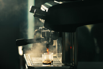 Two glasses of coffee  under coffee machine with water steam and light in background