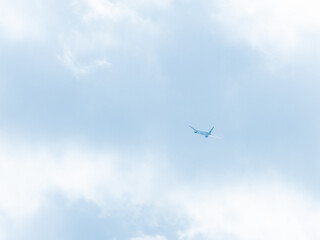 霞む淡い空を上昇する飛行機