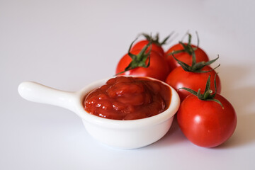 Fresh Otento sweet diamond tomatoes or cherry tomatoes and a white dipping bowl full of ketchup isolated on white background.