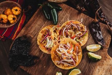 Bodegón de una deliciosa comida mexicana con chiles y vegetales al rededor en una tabla de madera