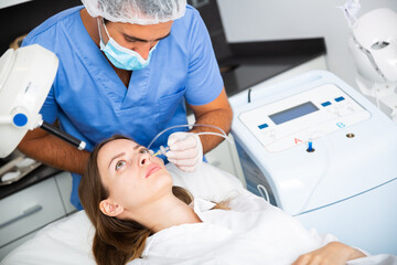 Young woman patient getting injections during carboxytherapy procedure in beautician office of aesthetic clinic