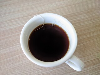 a cup of black coffee on a soft watural wooden table