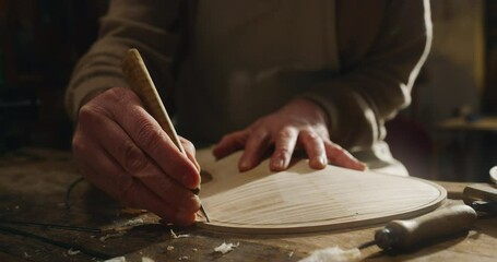 Cinematic shot of master artisan luthier working on creation of handmade fine quality wood violin in his creative workshop. Concept of spiritual instrument, handmade, art, orchestra, artisan, music.
