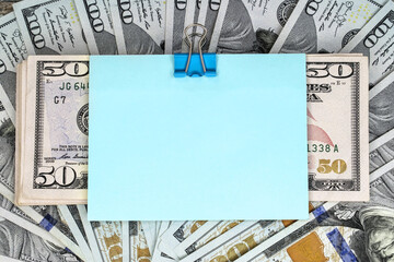 Business and financial concept. Hundred-dollar bills with fifty-dollar bills on top with a blank blue sheet of paper.