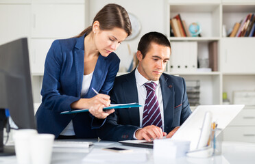 Head gives task to assistant at office at table