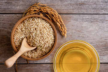 Rice bran oil extract with paddy and brown rice on wood table background. Top view. Flat lay.