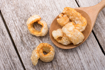 Fried pork snack ( pork rind, pork cracking ) isolated on wood table background. Top view. Flat lay.