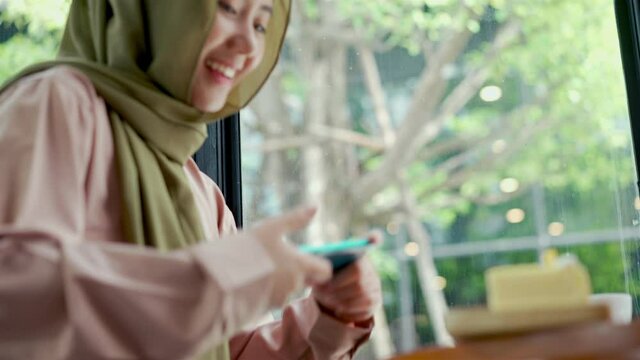 Happily young muslim woman take a picture cake with smartphone