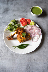 View from above of coriander leaf on chicken tandoori in a plate with condiments.