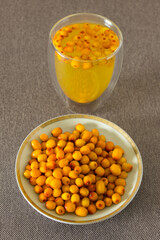 Seabuckthorn yellow berries in a plate and drink in glass. Vertical photo.