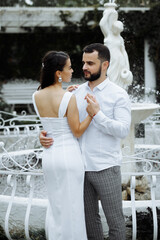 Naklejka premium Stylish couple gently hugging on the background of the fountain. Happy sensual wedding couple embracing. Romantic moments of newlyweds.