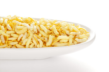 Crunchy Lemon Bhel in a white ceramic oval bowl made with Puffed Rice small besan sev. Pile of Indian spicy snacks (Namkeen)  under backlight side view 