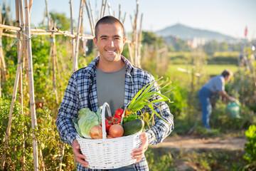 Happy farmer with basket of vegetables in the garden