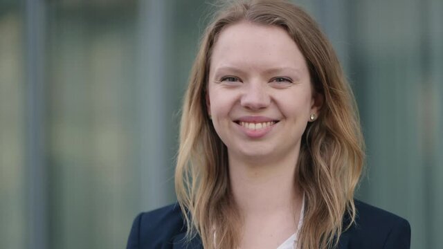 [4k] beautiful natural blonde business woman smiling at camera in front of office building