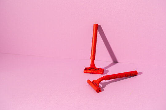Red disposable razor on pink background, copy space