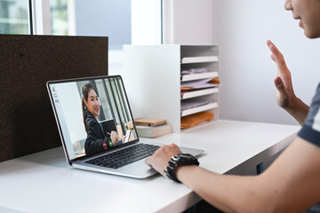 Cropped of man using laptop computer making video call with his colleague while sitting his modern home office.