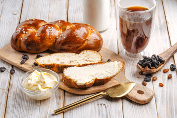 Side view on sweet raisins bun pigtail bread on the decorated wooden background