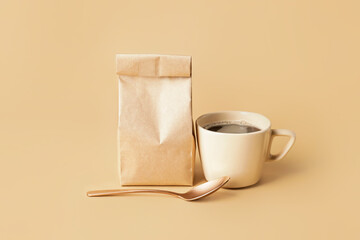 Paper bag and cup of hot coffee on color background