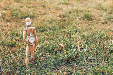 Wooden mannequin wearing medical mask with clock outdoors