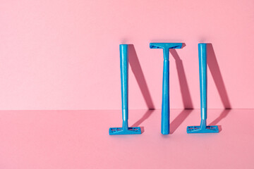 Blue disposable razors on pink paper background