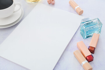 Blank magazine, lipsticks and cup of coffee on light background