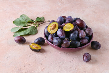 Plate with tasty plums on color background