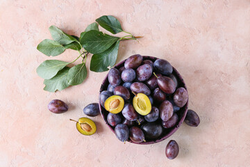 Plate with tasty plums on color background