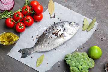 Raw dorado fish with ingredients on dark background