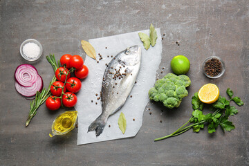 Raw dorado fish with ingredients on dark background