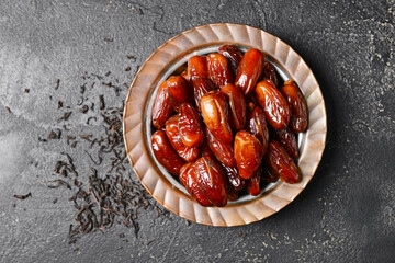 Plate with sweet dates on dark background