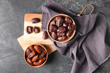 Bowls with sweet dates on dark background