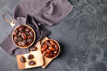 Bowls with sweet dates on dark background