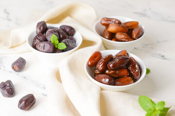 Bowls with sweet dates on light background
