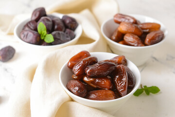 Bowls with sweet dates on light background
