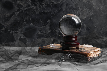Crystal ball of fortune teller and old book on dark background