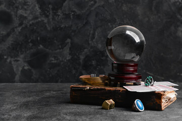 Fototapeta na wymiar Crystal ball of fortune teller, cards and old book on dark background