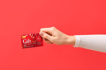 Female hand with gift card on color background