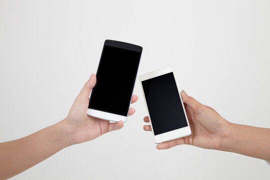 Cropped Hands Of People Holding Blank Mobile Phones Against White Background