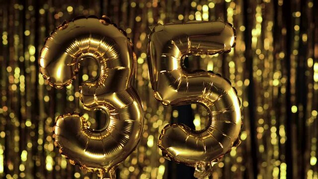 The golden number 35 thirty five is made from an inflatable balloon on a yellow background. One of the complete set of numbers. Birthday, anniversary, date concept