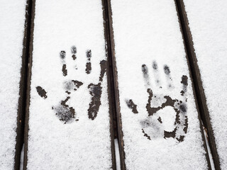 Imprints of hands in snow on a table outdoor