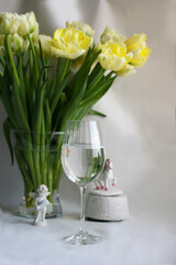 A glass of water on the background of a beautiful bouquet of tulips.