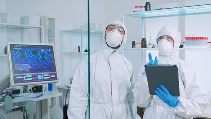 Team of scientists in ppe suit working in chemistry modern equipped laboratory using virtual reality. Doctors examining vaccine evolution with high tech researching diagnosis against covid19 virus