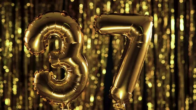 The golden number 37 thirty seven is made from an inflatable balloon on a yellow background. One of the complete set of numbers. Birthday, anniversary, date concept