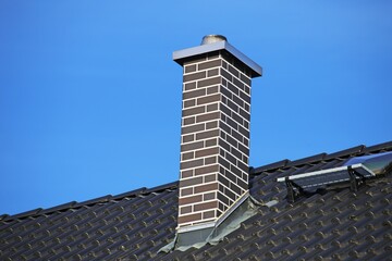 Mit Klinkersteinen verkleideter Schornstein an einem neu gedeckten Dach