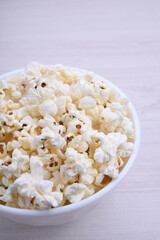 Salted popcorn in a bowl on a wooden table. Top view