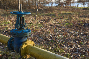 Old gas pipes with large overlapping taps are laid underground in the yard.