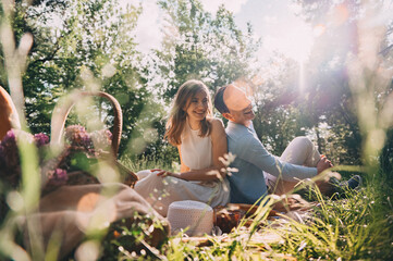 picnic for lovers. happy young couple spend time outdoors at sunset of the day. lovers have fun sitting on the bedspread in the forest. boy and girl on a romantic date at sunset